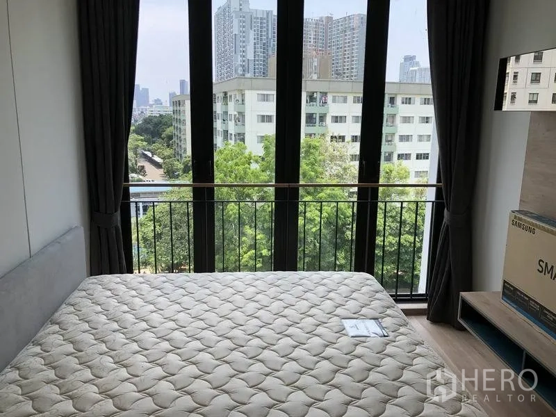 公寓 出租在Watthana, Bangkok - 主卧室配落地窗，俯瞰绿意与运河及城市楼景。