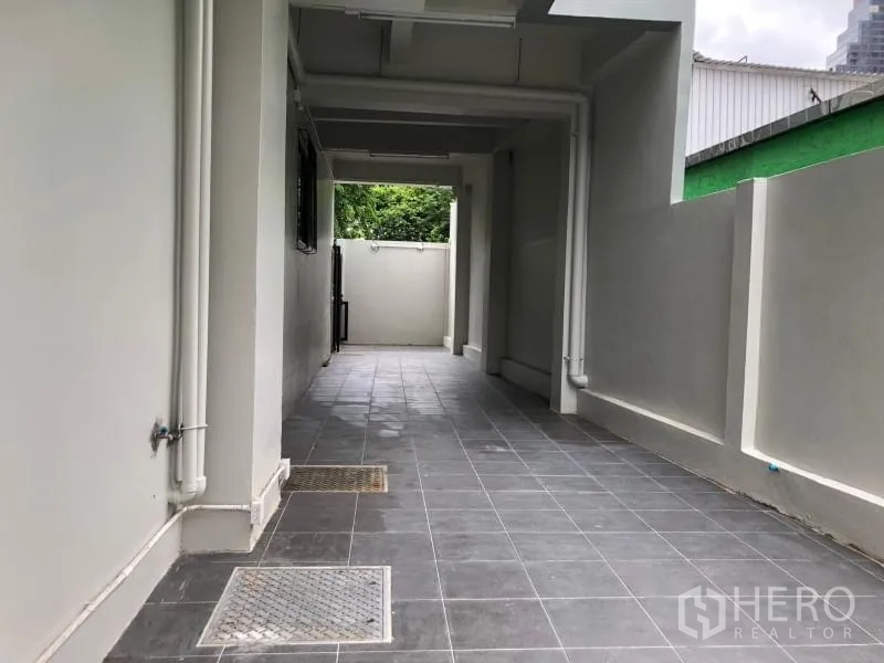 Office Space for rent in Bang Rak, Bangkok - Covered side walkway with grey floor tiles and exposed service pipes.