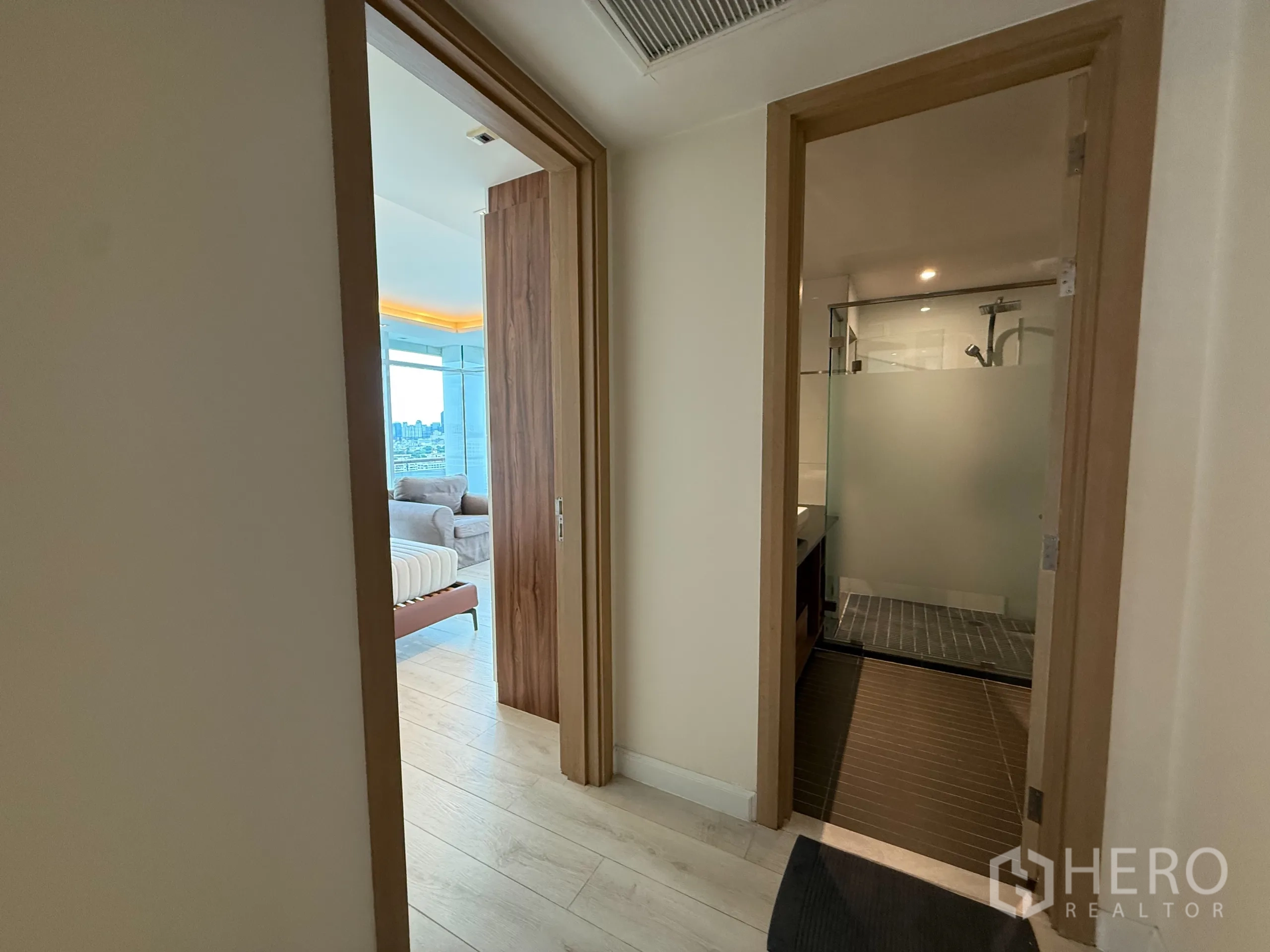 Condominium for rent in Phaya Thai, Bangkok - Hallway with light wood flooring leading to bedroom and bathroom.
