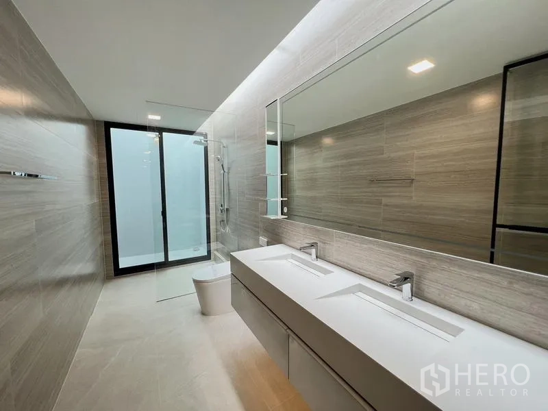Detached House for rent or sale in Saphan Sung, Bangkok - Sleek bathroom featuring a double-sink vanity, glass shower, and full-width mirror.