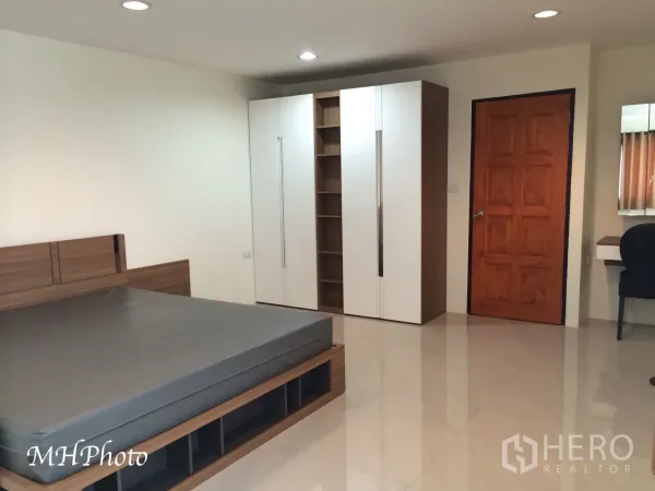 Condominium for rent in Watthana, Bangkok - Large bedroom with modern bedframe, built-in wardrobe and glossy tile flooring.