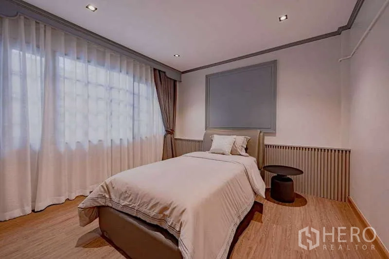 Detached House for rent or sale in Phra Khanong, Bangkok - Secondary bedroom with a single bed, wide windows, and soft lighting.