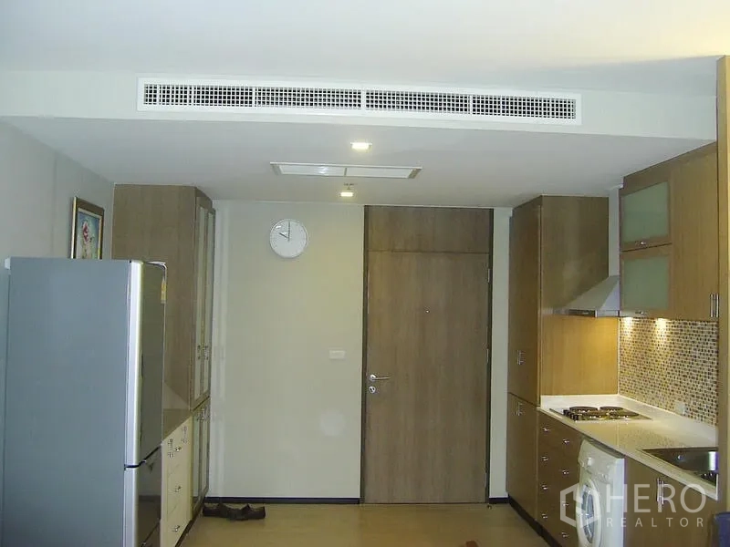 Condominium for rent in Khlong Toei, Bangkok - Entry and open kitchen with cooktop, range hood, mosaic backsplash and in-unit washing machine.
