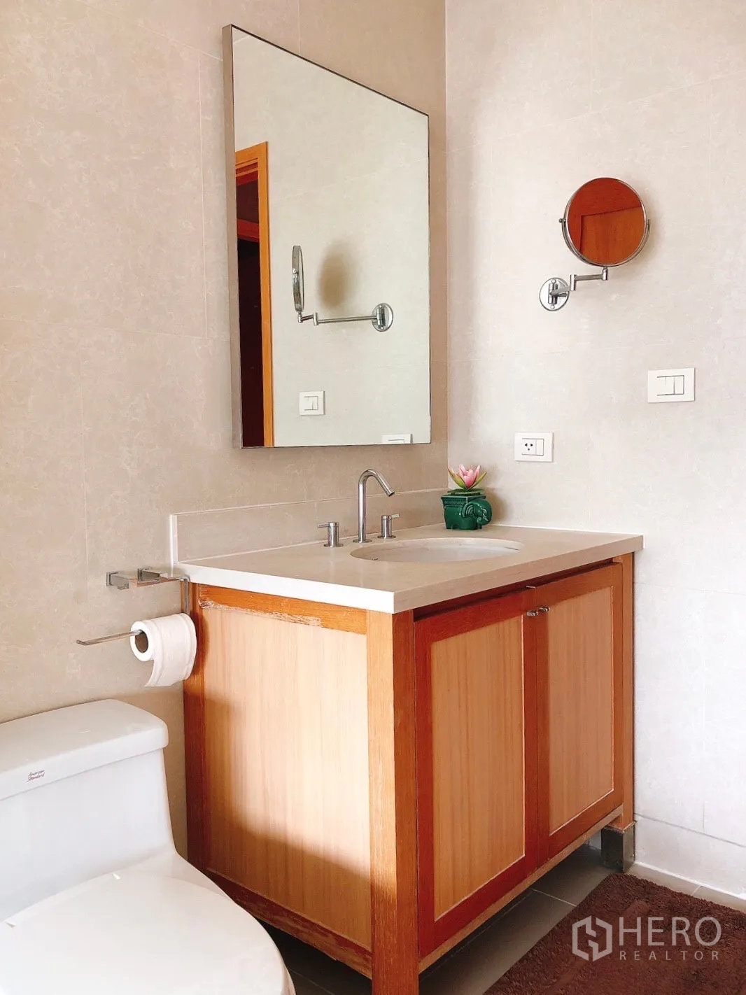 Condominium for rent in Khlong Toei, Bangkok - Modern bathroom vanity with mirror, sink and toilet.