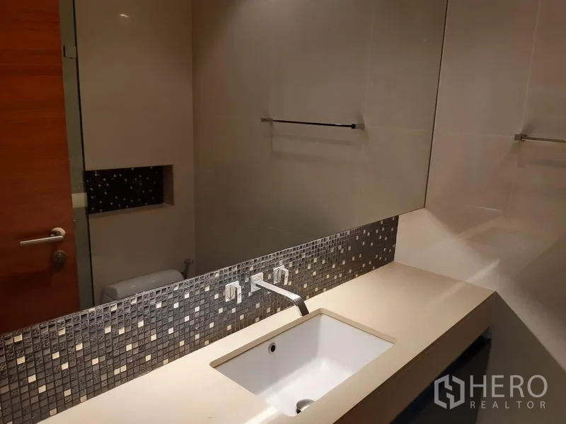 Condominium for rent or sale in Khlong Toei, Bangkok - Bathroom vanity with long mirror, mosaic backsplash and under-mount sink.