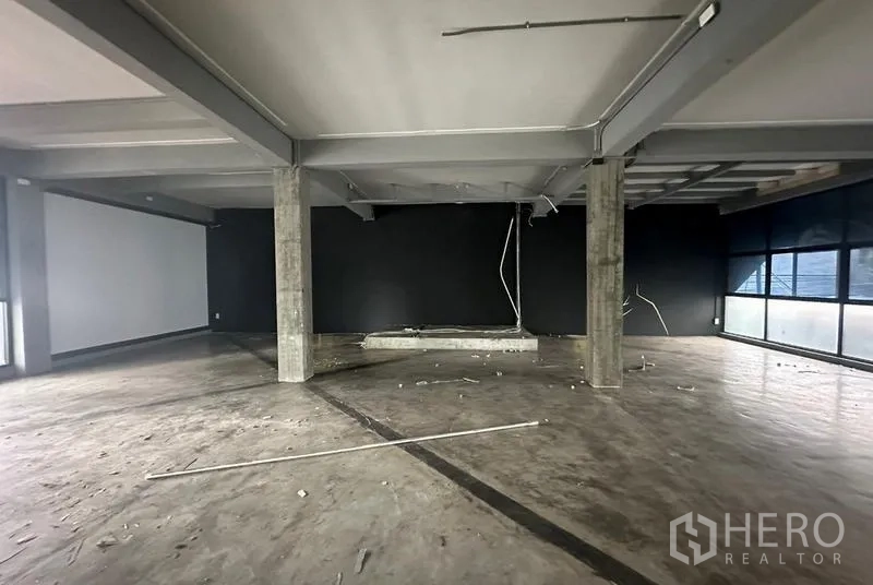 Retail Space for rent - Spacious unit featuring a black accent wall, ceiling beams and concrete flooring ready for fit-out.