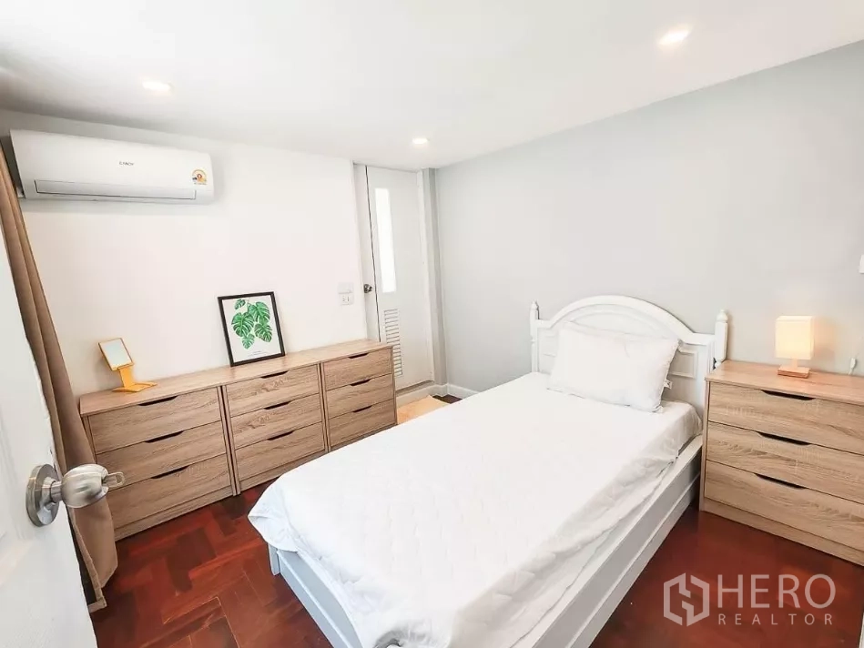 Detached House for rent in Yan Nawa, Bangkok - Bright guest bedroom with white bed, wooden dressers, and air conditioning.