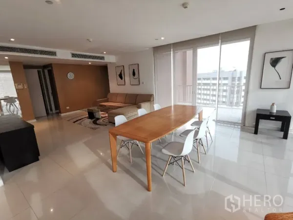 公寓 出租在Watthana, Bangkok - 开放式客餐厅，落地窗与阳台，木质餐桌白色椅，L形沙发与城市景观。