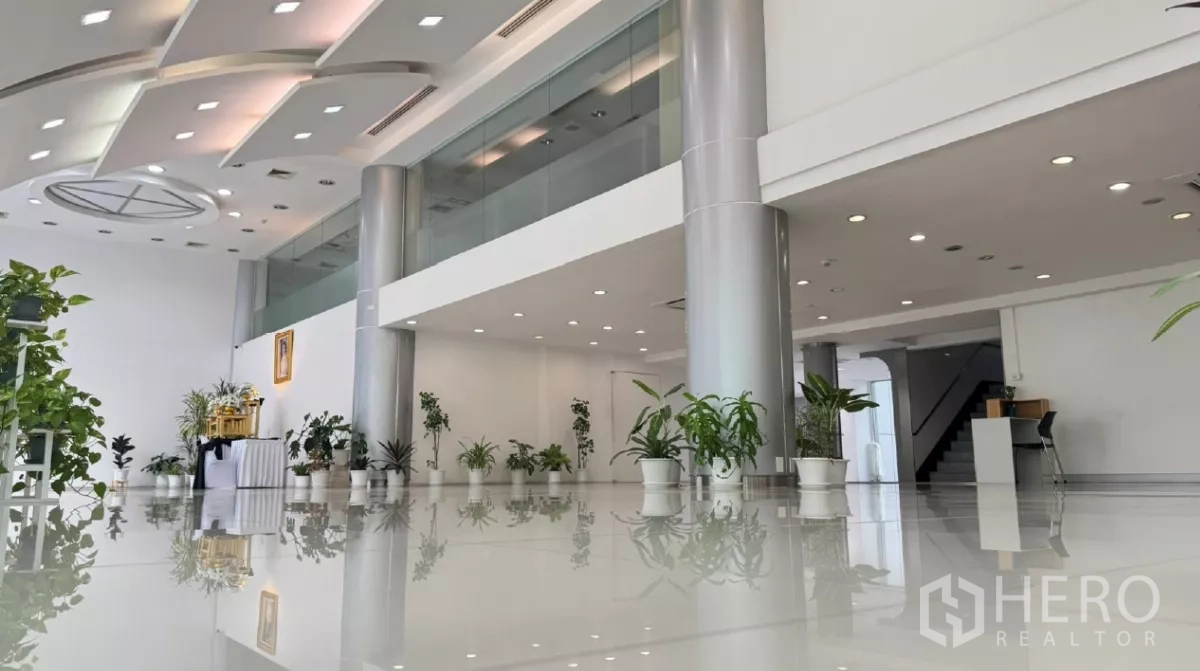 Retail Space for rent in Huai Khwang, Bangkok - Showroom with mezzanine-style glass railing, sleek silver columns and a wide open floor for flexible layouts.