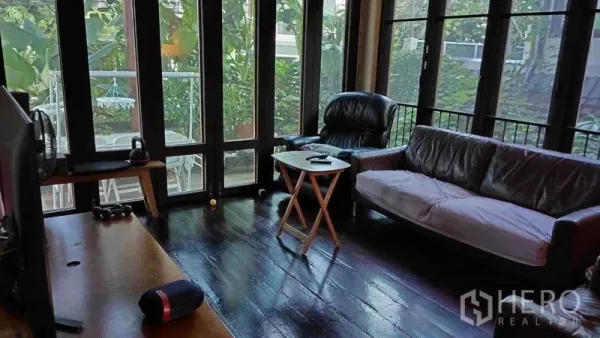 Detached House for sale in Suan Luang, Bangkok - Lounge with dark hardwood floors, floor‑to‑ceiling glass doors and sofas overlooking lush greenery.