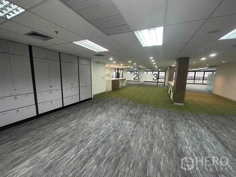 Office Space for rent in Khlong Toei, Bangkok - Collaboration zone with green carpet, built‑in storage and a service counter connecting to the main floor.