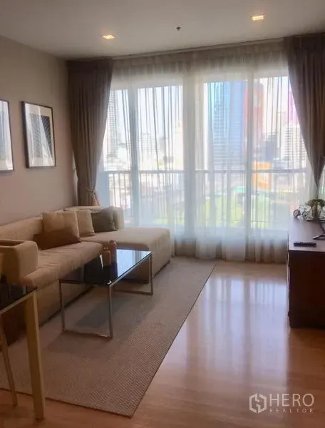 公寓 出租在Sathon, Bangkok - 客厅配落地窗与纱帘，城市天际线景观，旁有沙发与电视柜