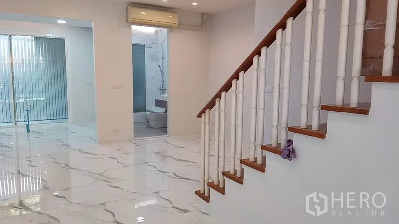 Townhouse for rent in Yan Nawa, Bangkok - Living space showing staircase, recessed lights and access to a bathroom.