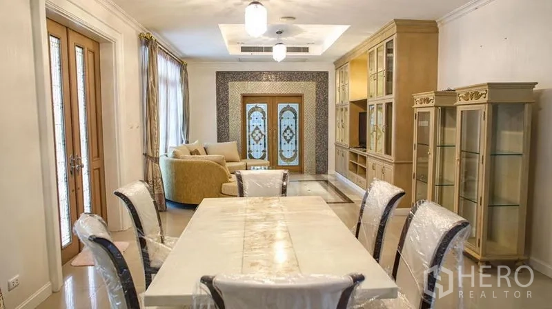 Detached House for rent in Bang Phli, Samut Prakan - Dining area with long table and chairs facing the living room and decorative doors.