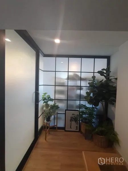 联排别墅 出售在Lat Phrao, Bangkok - 走廊一侧为磨砂玻璃隔断，点缀室内绿植。