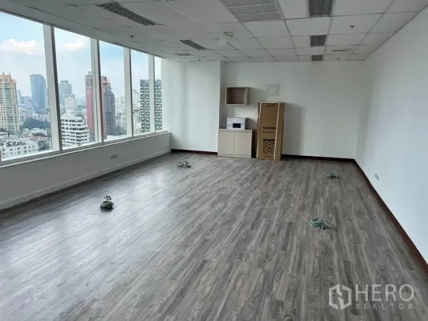 办公空间 出租在Watthana, Bangkok - 角落办公区配大面积窗户与小型茶水柜，享全景城市视野。