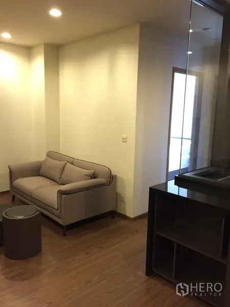 Condominium for rent in Watthana, Bangkok - Cozy sofa corner with recessed lighting, wood floors and round nesting stools.