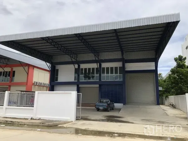 Factory for rent or sale in Bang Sao Thong, Samut Prakan - Modern factory exterior with a large covered loading bay, wide driveway, and roll-up door in Bang Sao Thong.