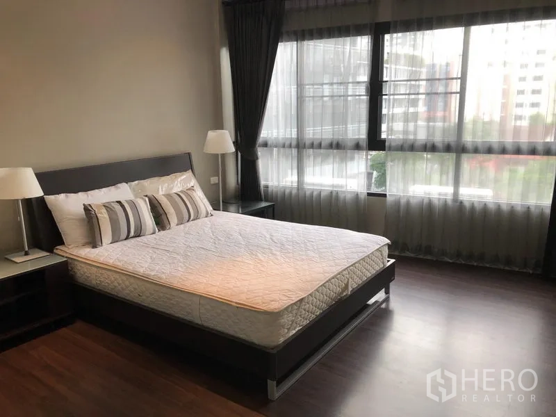公寓 出租在Khlong Toei, Bangkok - 宽敞卧室，木地板，大窗搭配纱帘与双人床。
