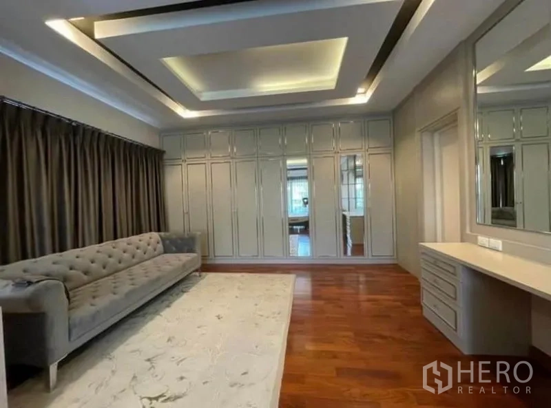 Detached House for rent or sale in Bang Phli, Samut Prakan - Master dressing area with long sofa, mirrored wall of wardrobes and built-in vanity.