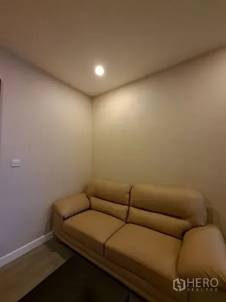 Condominium for rent in Bang Rak, Bangkok - Cozy corner with beige leather sofa under recessed lighting.