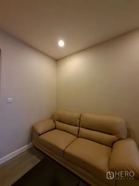 Condominium for rent in Bang Rak, Bangkok - Cozy corner with beige leather sofa under recessed lighting.