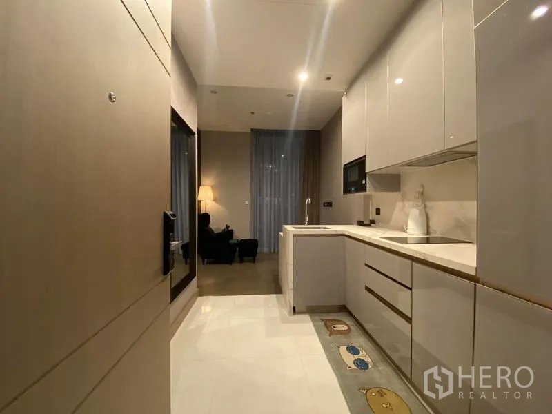 公寓 出租在Huai Khwang, Bangkok - 从入口望向细长厨房，延伸至柔和灯光的起居区。