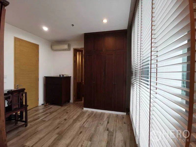 公寓 出租或出售在Bang Rak, Bangkok - 卧室设深色木衣柜，宽幅百叶与木纹地板。