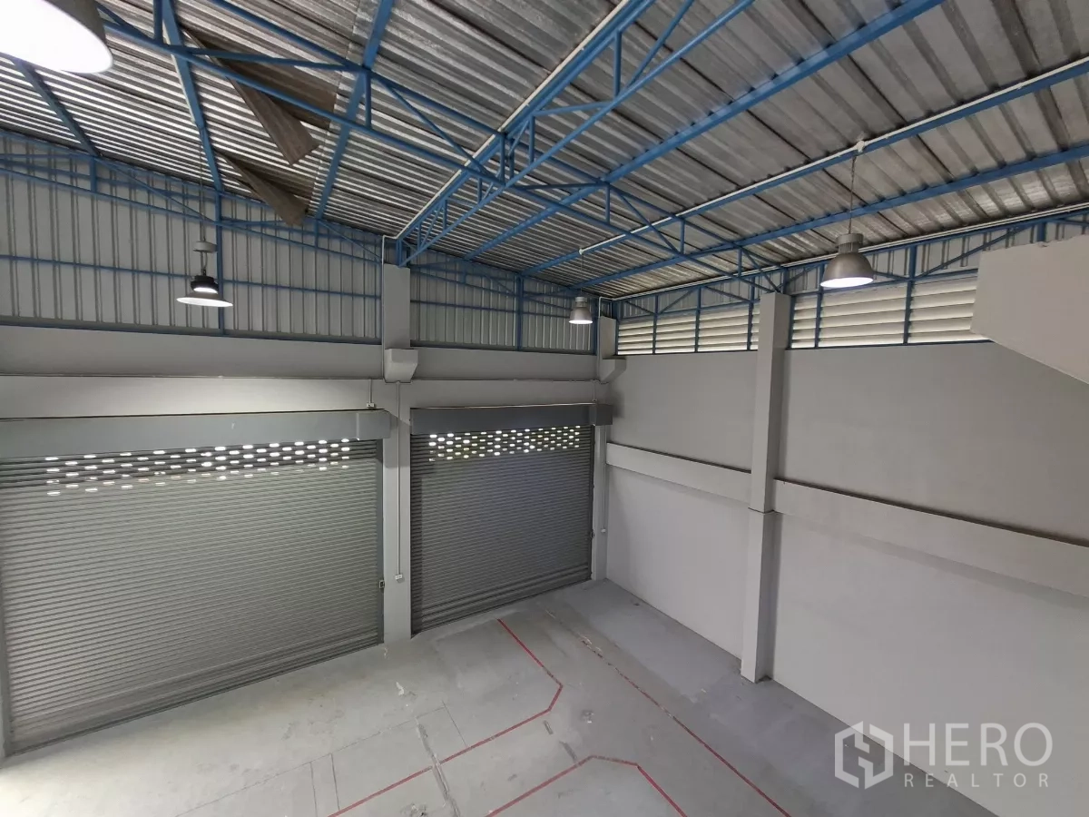 Warehouse for rent in Suan Luang, Bangkok - Mezzanine perspective across the high‑bay warehouse and several roller shutter doors.