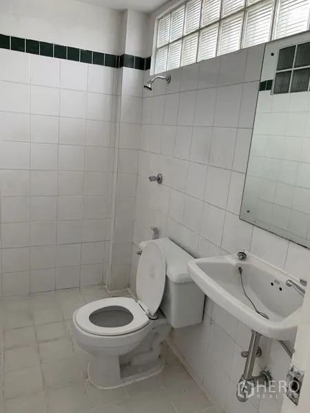 Shophouse for rent in Bang Na, Bangkok - Second tiled bathroom with toilet, sink, and glass-block clerestory window.