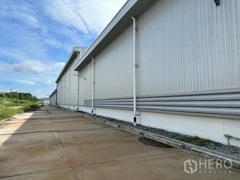 Factory for rent in Bang Sao Thong, Samut Prakan - Side service road beside the metal-clad building with drainage and gutters.