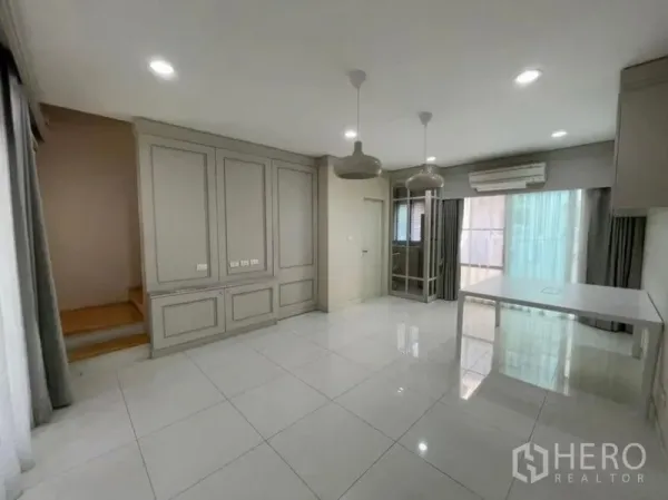 Townhouse for sale - Ground-floor living–dining space with staircase, air-conditioning, and sliding doors to the terrace.