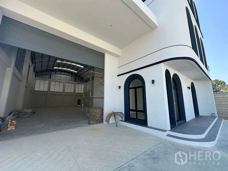 工厂 出售在Lam Luk Ka, Pathum Thani - 装卸区与办公室入口，紧邻超大卷帘门。