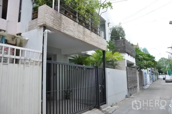 联排别墅 出租或出售在Watthana, Bangkok - Ekkamai联排别墅外观，带安全铁门、遮蔽车位与阳台花槽，位于安静小巷。