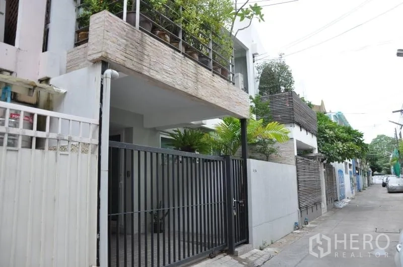 联排别墅 出租或出售在Watthana, Bangkok - Ekkamai联排别墅外观，带安全铁门、遮蔽车位与阳台花槽，位于安静小巷。