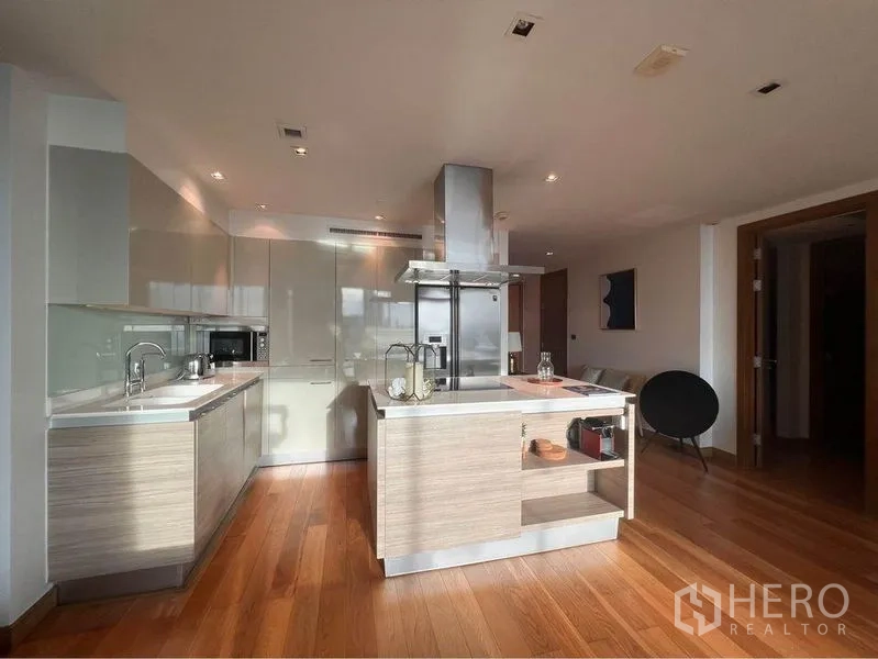 Condominium for rent or sale in Phaya Thai, Bangkok - Open-plan kitchen with island, stainless hood, glossy cabinets and warm wood floors in a modern Bangkok condo.