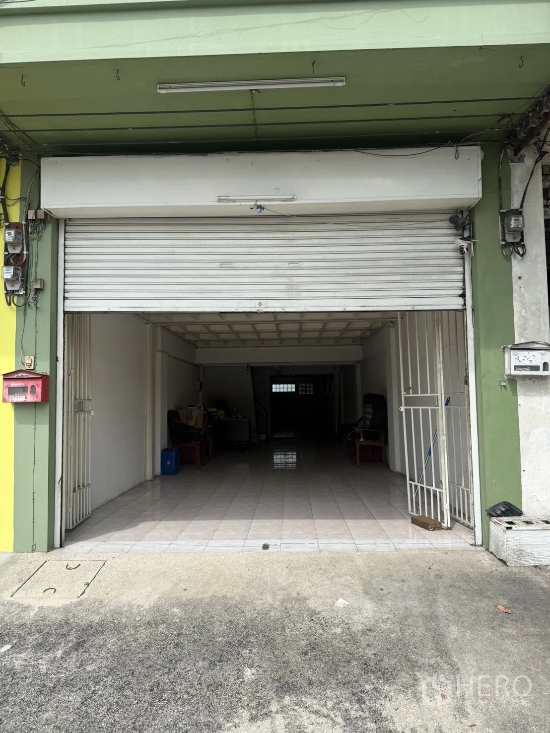 Shophouse for rent in Pak Kret, Nonthaburi - Street-level shophouse facade with white roller shutter and tiled entry.