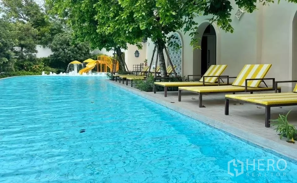 Detached House for rent in Lat Krabang, Bangkok - Community swimming pool with sun loungers, shade trees and a children’s slide.
