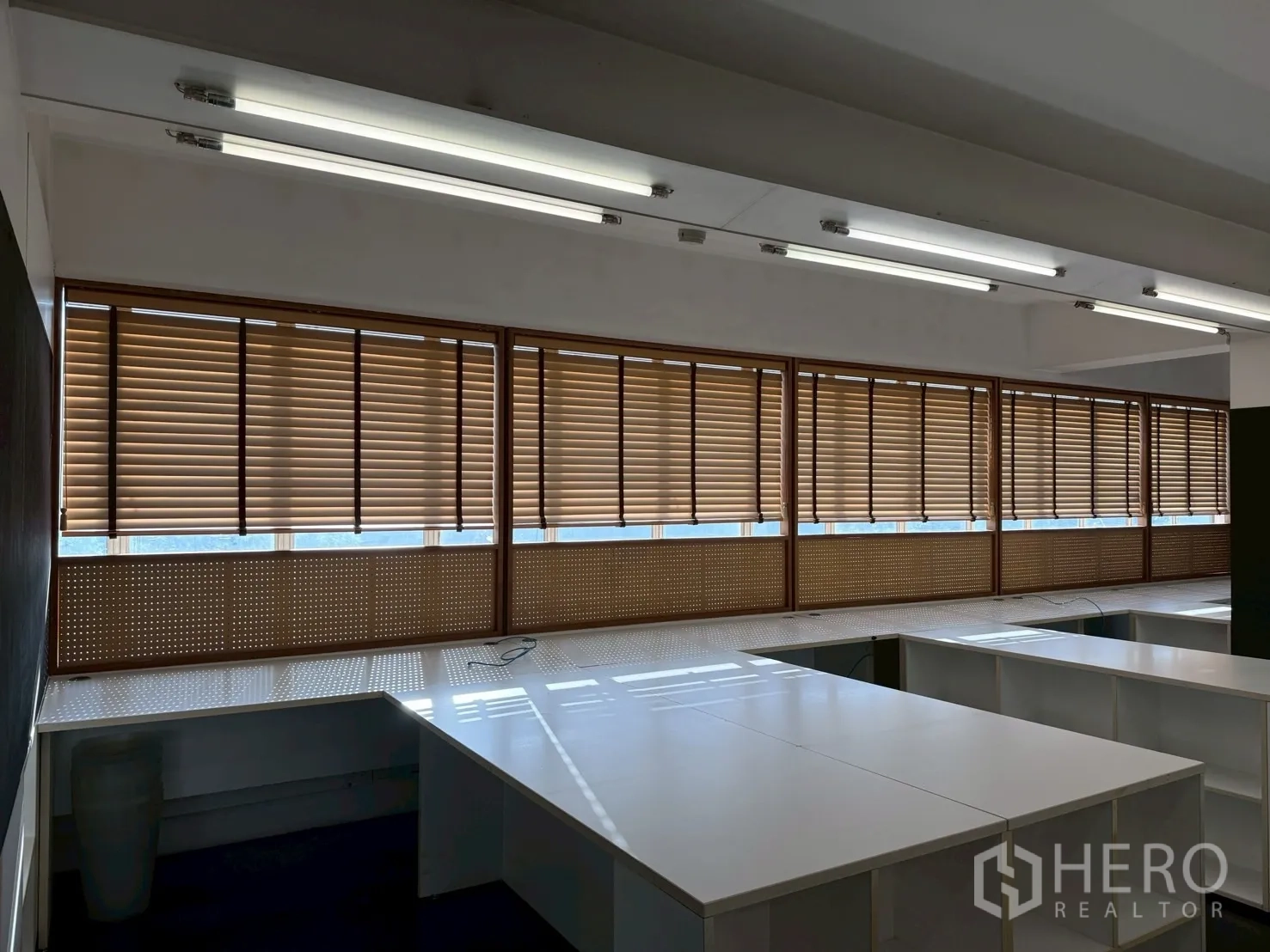 ออฟฟิศ for rent in Huai Khwang, Bangkok - หน้าต่างบานยาวพร้อมมู่ลี่ไม้ เหนือโต๊ะทำงานมุม ในพื้นที่สำนักงานทันสมัย