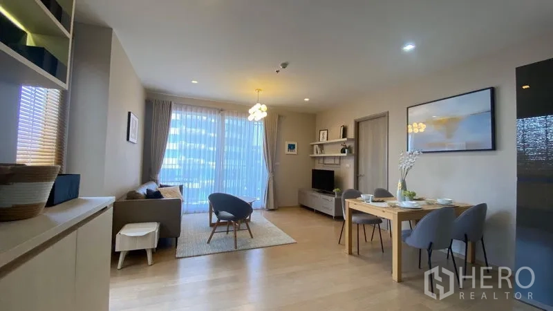 公寓 出租在Watthana, Bangkok - 宽敞起居与用餐区，木地板、大窗与电视柜