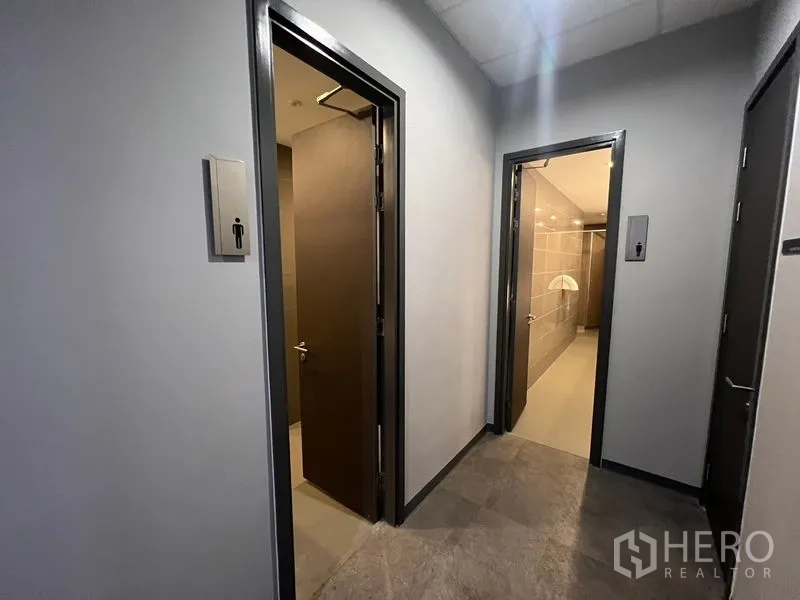 Office Space for rent - Hallway leading to separate male and female restrooms in the office building.