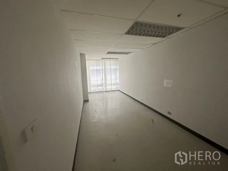办公空间 出租在Khlong Toei, Bangkok - 狭长房间，亮面地砖、吊顶日光灯与窗边竖百叶。