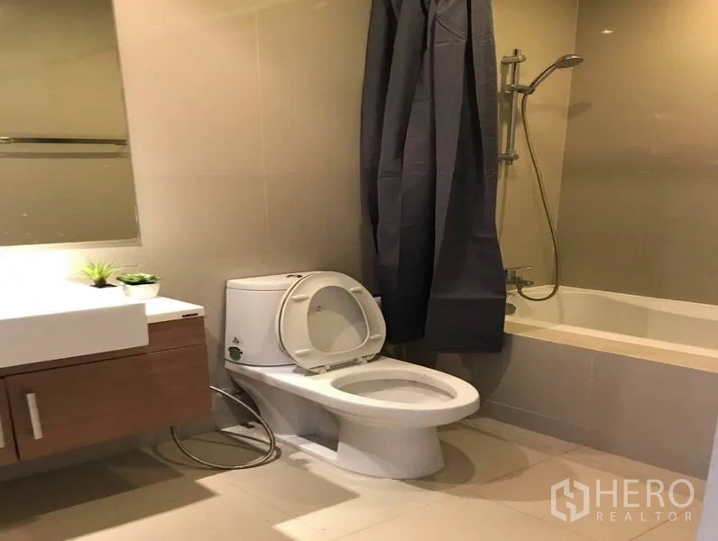 Condominium for rent in Bangkok - Bathroom with bathtub, shower, vanity, and toilet in neutral tones.