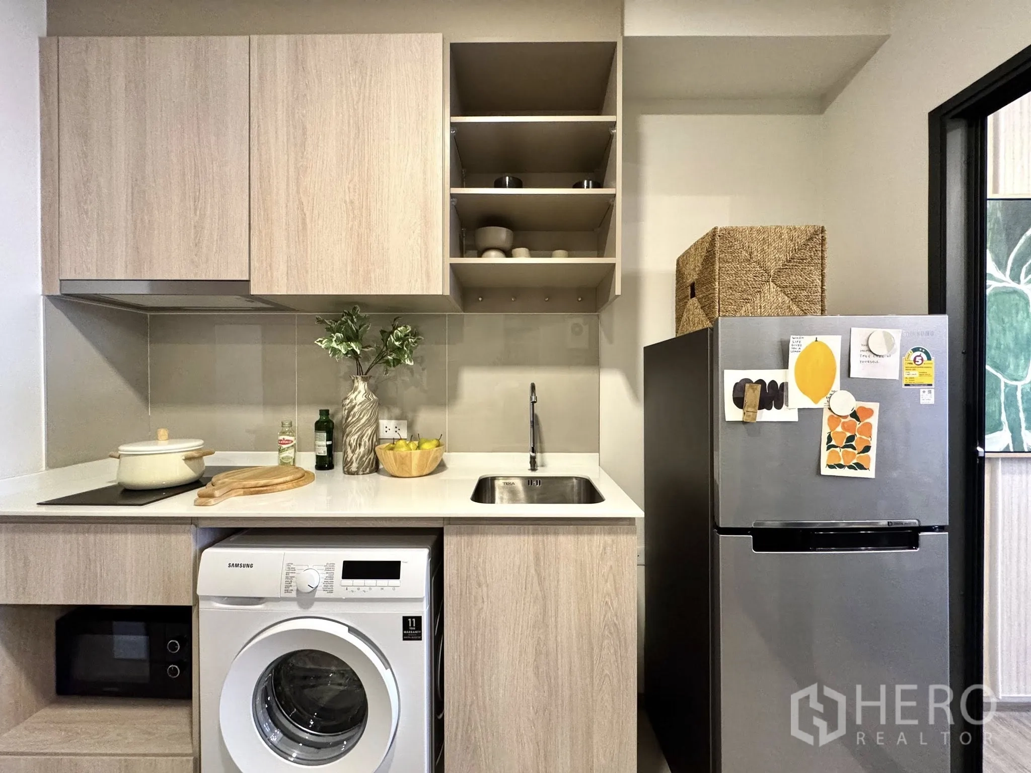 Condominium for rent in Watthana, Bangkok - Compact kitchen with upper cabinets, open shelves, washer, microwave, and fridge.