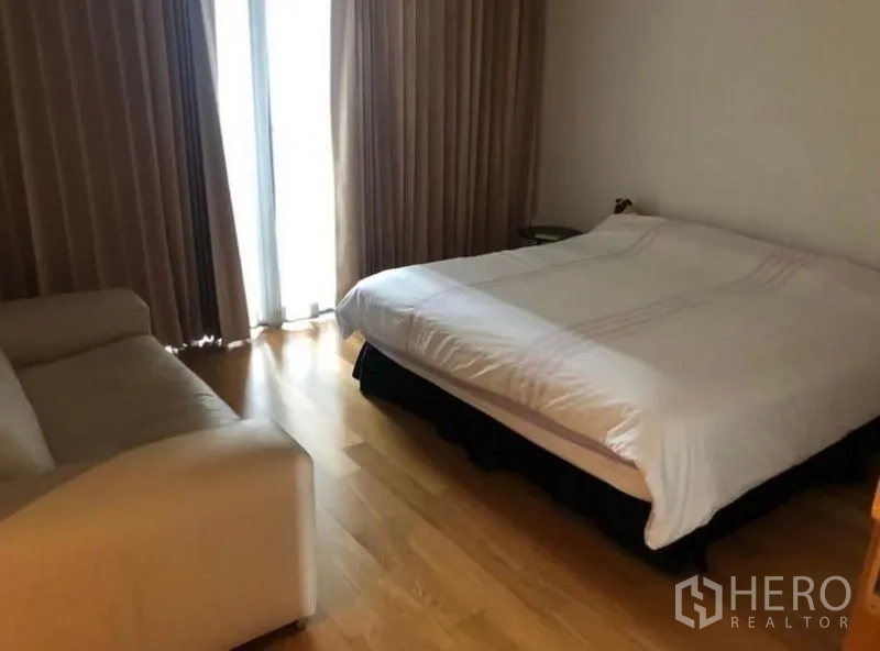 Condominium for rent in Sathon, Bangkok - Cozy bedroom with hardwood floors, sofa and curtained balcony door