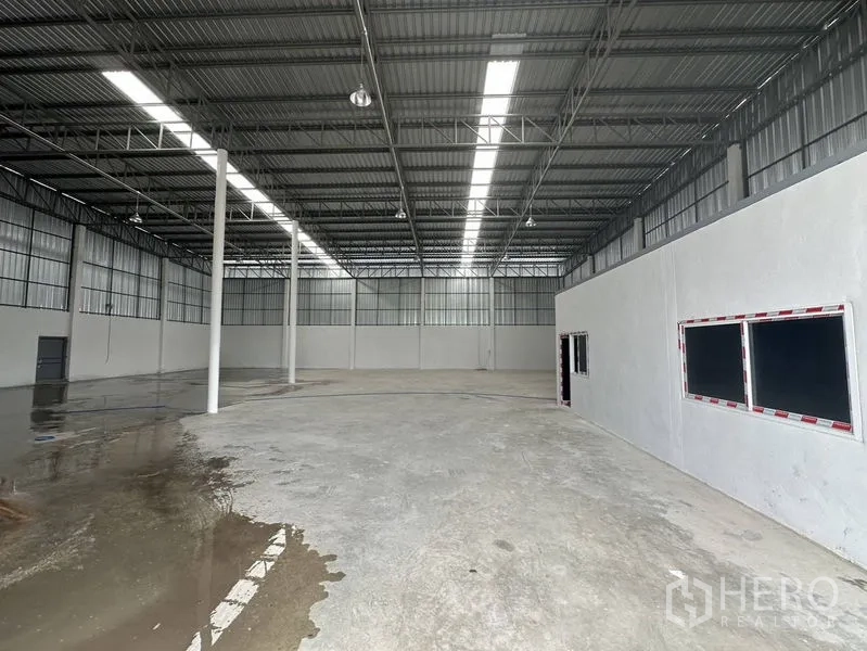 Warehouse for rent in Sai Noi, Nonthaburi - Spacious warehouse interior with high steel roof, skylights and an internal office block.