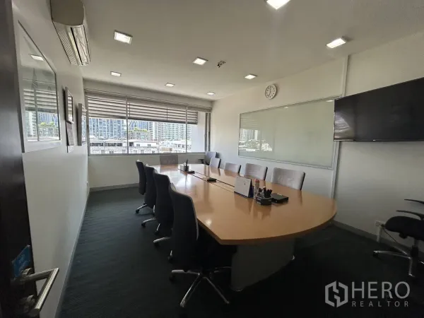Office Space for rent - Large boardroom with long conference table, whiteboard, TV display and city-view windows.