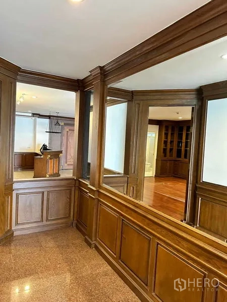 Condominium for rent in Bangkok - Corridor with mirrored wood paneling overlooking the living space.