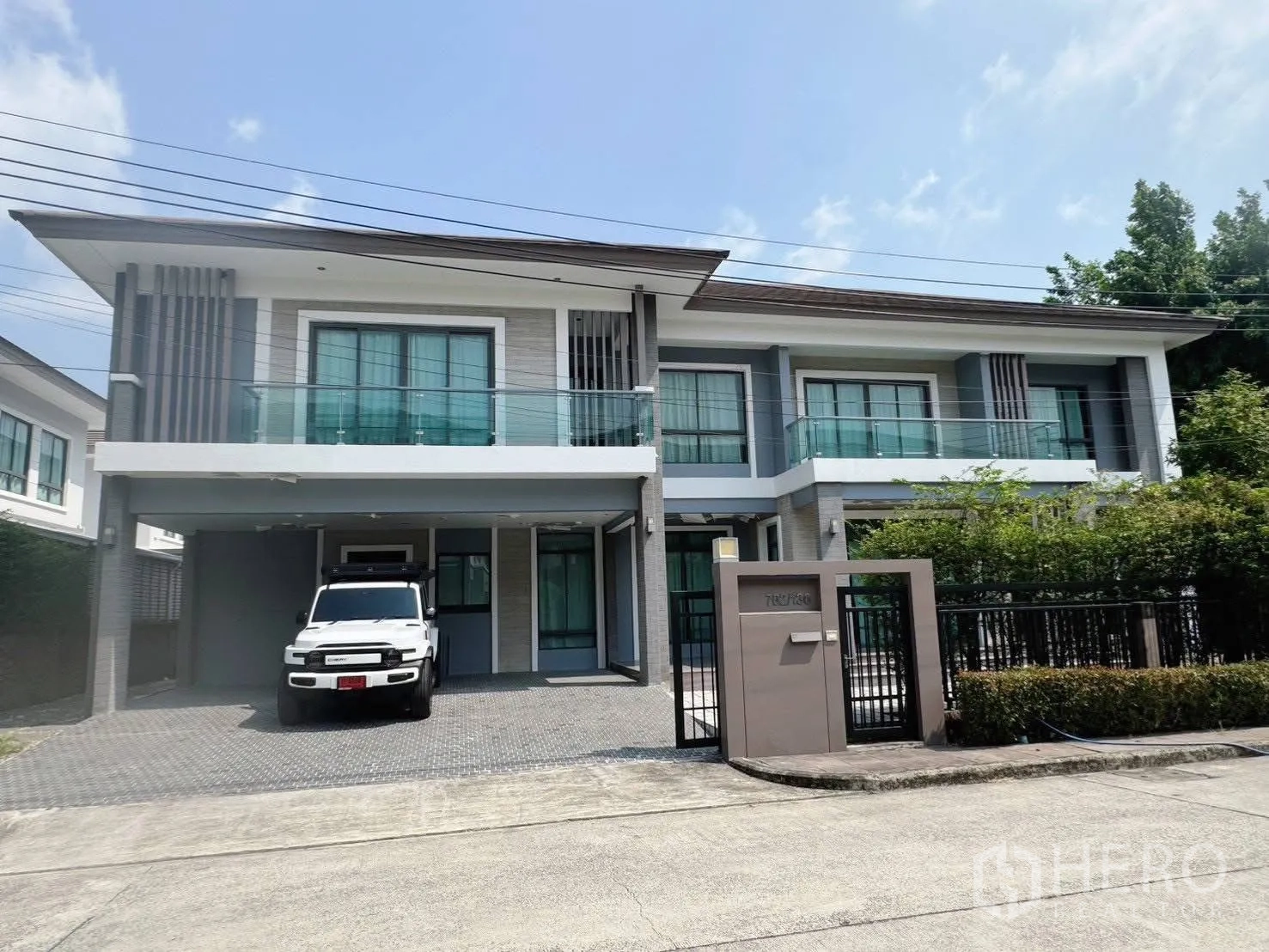 บ้านเดี่ยว for rent or sale in Suan Luang, Bangkok - ด้านหน้าบ้านสองชั้นสมัยใหม่ มีระเบียง โรงจอดรถ และประตูรั้ว