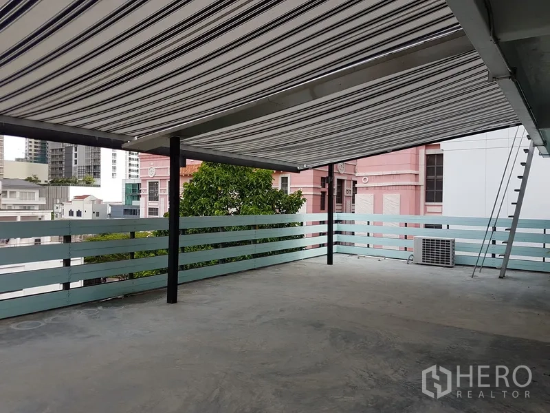 Home Office for sale in Khlong Toei, Bangkok - Rooftop terrace with striped retractable awning and city outlook.